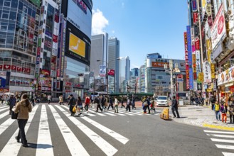 Large intersection with billboards and colorful signs at shops and restaurants, busy downtown with