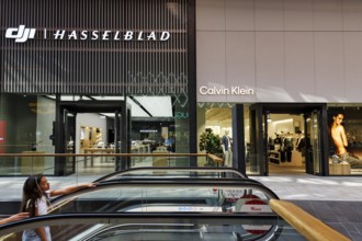 Shop window with logo, Hasselblad and Calvin Klein lettering, escalator, Westfield Überseequartier,