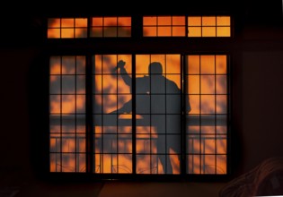 Shadow of a man climbing over balcony railings, burglar with knife, assassin, ninja, on the balcony