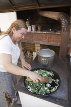 Serbian woman cooking przeno or traditional Serbian dish in her kitchen, Vrmdza, Sokobanja, Serbia