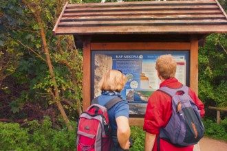 Tourist couple in front of information board of Cape Arkona, coast of Rügen, largest German island,