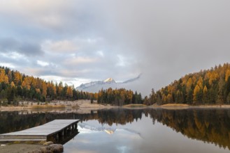 Lake Staz against mountain backdrop, mountain lake, mixed forest with larch (Larix) in autumn,