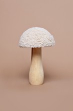 Single wooden and textile decorative mushroom object on beige background