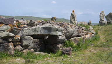 Stone wall with stones stacked on it in a green landscape, stone circle, megaliths, Zorats Karer,