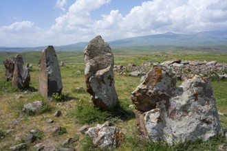 Set of stones in a vast landscape with mountains and clouds in the background, stone circle,