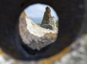 Stone block with hole that allows a view of stones and landscape behind it, stone circle,