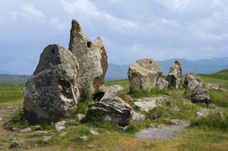 Protruding stones in a meadow under a cloudy sky, stone circle, megaliths, Zorats Karer,