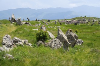 Stone blocks on a green meadow with hills and mountains in the background, stone circle, megaliths,