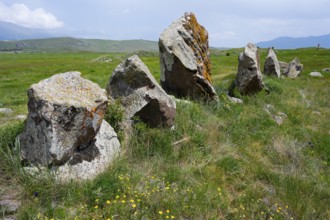 Stone formations on a green meadow under a blue sky with clouds, stone circle, megaliths, Zorats