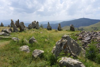 Stone formations in a meadow with a view of cloudy mountains, stone circle, megaliths, Zorats