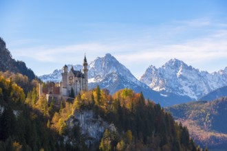 Neuschwanstein Castle in the midst of an atmospheric autumn landscape with high snow-covered
