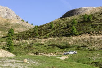 Porsche GT3 sports car drives on mountain road above tree line Col de d' Izoard l' Izoard l'Izoard