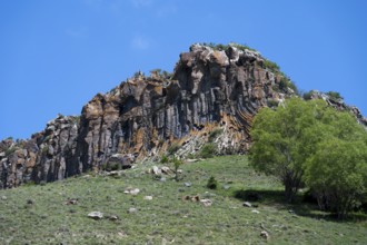 Mighty rock formation with lush greenery and clear skies, radiating peace and natural beauty,