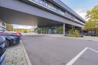 Parking lot in front of a modern, grey office building under clear skies, Calw District Office,