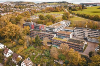 Multi-storey building complex with colorful autumn trees in rural surroundings, Calw District