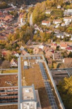 Building with a flat roof and solar cells next to an idyllic, autumnal urban landscape, Calw