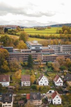 View of village with autumn trees and fields, dominating clouds in the sky, Calw District Office,