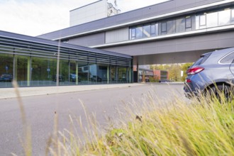 Modern office building with grey façade, surrounded by autumn grass and a parking lot, Calw