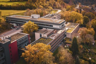 Autumn aerial view of a large building complex in the middle of forest and village, Calw District