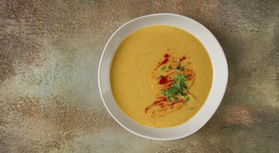 Pumpkin cream soup, in a white bowl on a textured background, top view, homemade, no people, rustic