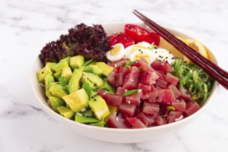 Fresh poke bowl, with tuna, avocado, and vegetables, served on a white plate