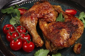 Grilled fried chicken legs, served with fresh cherry tomatoes and herbs, on a plate, homemade, no