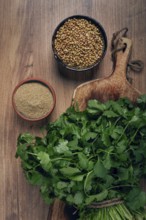 A bunch of fresh cilantro, coriander seeds and powder bowls, close-up, top view, no people, food