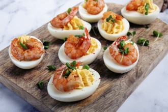 Boiled eggs stuffed with yolk and seasoned with mayonnaise, stuffed eggs with shrimp, on a wooden