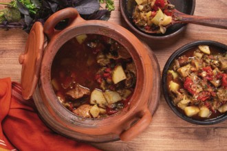 Chanakhi, a Georgian dish. in a clay pot, on a wooden table, stewed meat with vegetables, homemade,