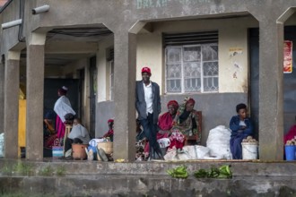 Street scene, people waiting outside houses for the rain to end selling vegetables, Kisoro, Uganda