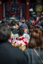 Young Japanese woman wearing kimono surrounded by numerous visitors on Nakamise-dori shopping