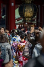 Two young Japanese woman wearing kimono surrounded by numerous visitors on Nakamise-dori shopping