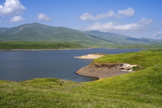 A calm lake surrounded by green hills and mountains under a blue sky with clouds, Spandaryan