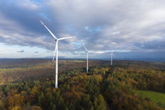 Wind turbines tower above an autumnal forest under a cloudy sky, near Schorndorf, Remstal,