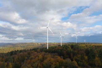 Three wind turbines above a colorful autumn forest under a cloudy sky, near Schorndorf, Remstal,