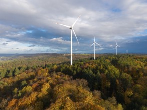 A wind farm rises above an autumnal forest under a cloudy sky, near Schorndorf, Remstal,