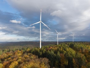 Three wind turbines above an autumnal forest against a cloudy sky, near Schorndorf, Remstal,