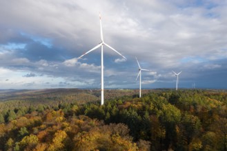 Wind turbines stand in a colorful autumn forest under a changing sky, near Schorndorf, Remstal,