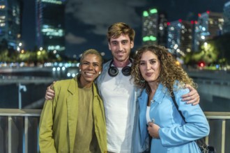 Diverse group of three friends standing arm in arm, smiling at the camera during a casual night out