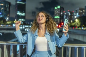 Young woman with curly hair wearing headphones and holding a smartphone, actively dancing to music