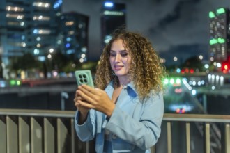 Young woman smiling, scrolling on her smartphone, enjoying connectivity and social media on a city