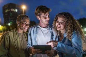 Diverse young friends gathering closely, smiling and interacting with a glowing digital tablet on a