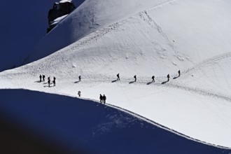 A group of mountaineers runs across a snow-covered mountain, Aiguille du Midi, Chamonix-Mont-Blanc,