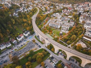 Aerial view of a city with a curved bridge surrounded by autumn trees and residential buildings,