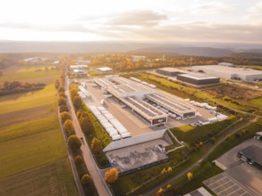 Industrial park with numerous buildings surrounded by green fields and warm skies, Nagold, Black