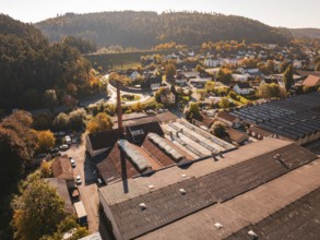An industrial area with factory buildings and a chimney, nestled in an autumn landscape, Nagold,