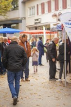 Families and individuals explore the market stalls in a busy pedestrian zone, Streuobstmarkt,