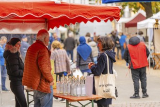Woman engaged in conversation at a stand with bottles and decorations at a market, traditional