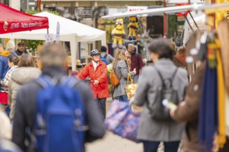 Lively market with people wearing winter clothes, surrounded by various stalls and decorations,