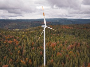 Wind turbine high above a colorful autumn forest on a hill, Simmersfeld wind farm, Germany